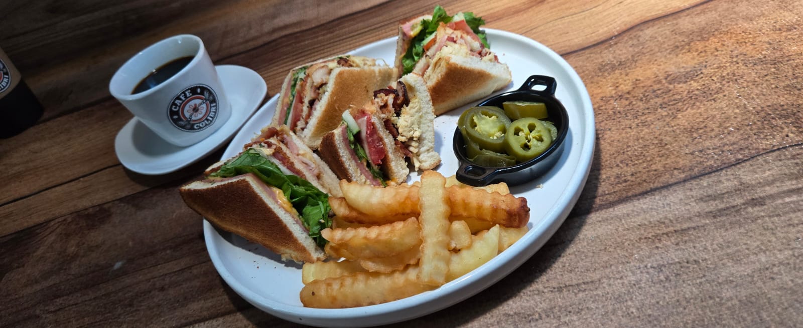 Club sándwich con papas acompañado de café en Café Colibrí